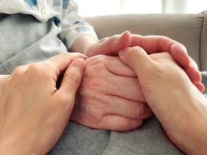 高齢者の手を包む介護職員の手
